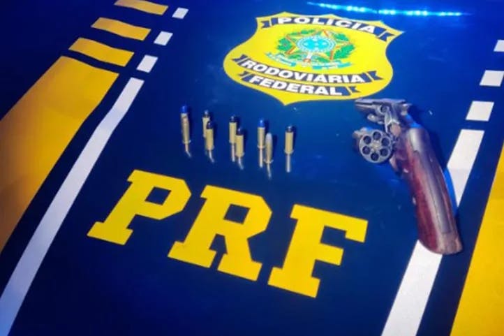 Imagem colorida mostrando muniçõe e o revólver 38 sobre o capô de uma viatura da Polícia Rodoviária Federal