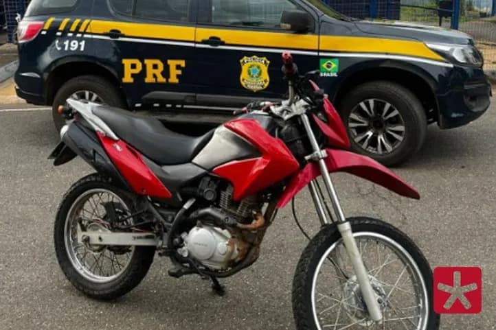imagem colorida, com motocicleta vermelha,  ao lado da vitura da PRF em frente ao posto de fiscalização