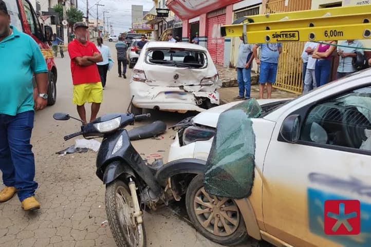 Imagem colorida mostrando local do acidente, com três vículos danificados e diversos curiosos ao lado