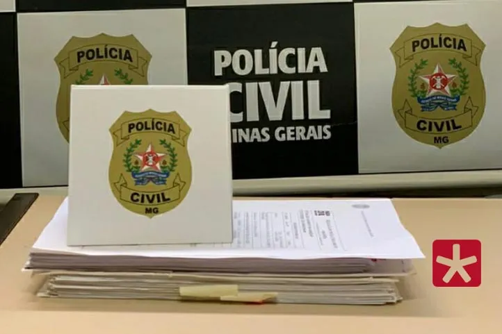 imagem colorida mostrando folhas do inquérito sobre uma mesa, com brasões da Polícia Civil em um baner logo atrás e também em cima das folhas.