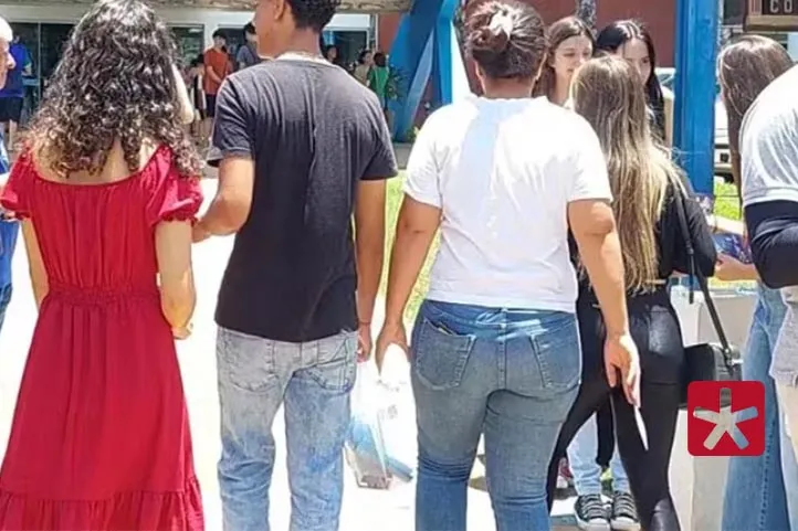 imagem colorida mostrando estudantes de costas entrando pelo portão do local de provas do Enem 
